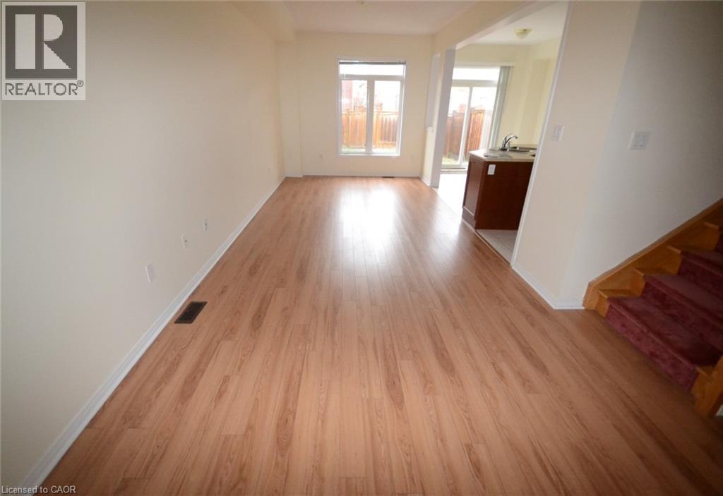 A room with wooden flooring and a staircase on the right side.