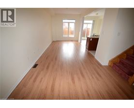A room with wooden flooring and a staircase on the right side.