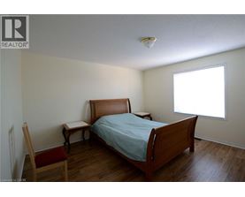 A bedroom with a bed, chair, and window.
