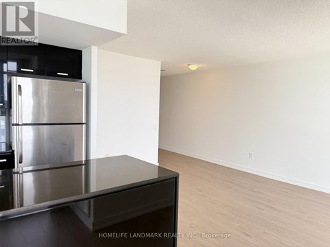 A kitchen with a stainless steel refrigerator and a black countertop.