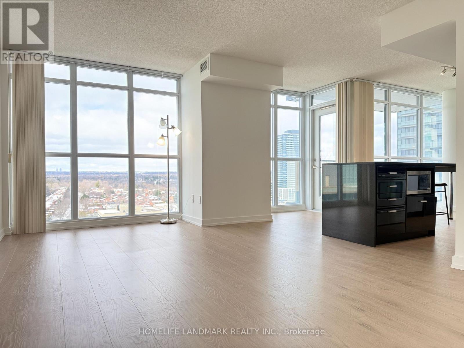 A spacious living room with a view of the cityscape outside the large windows.