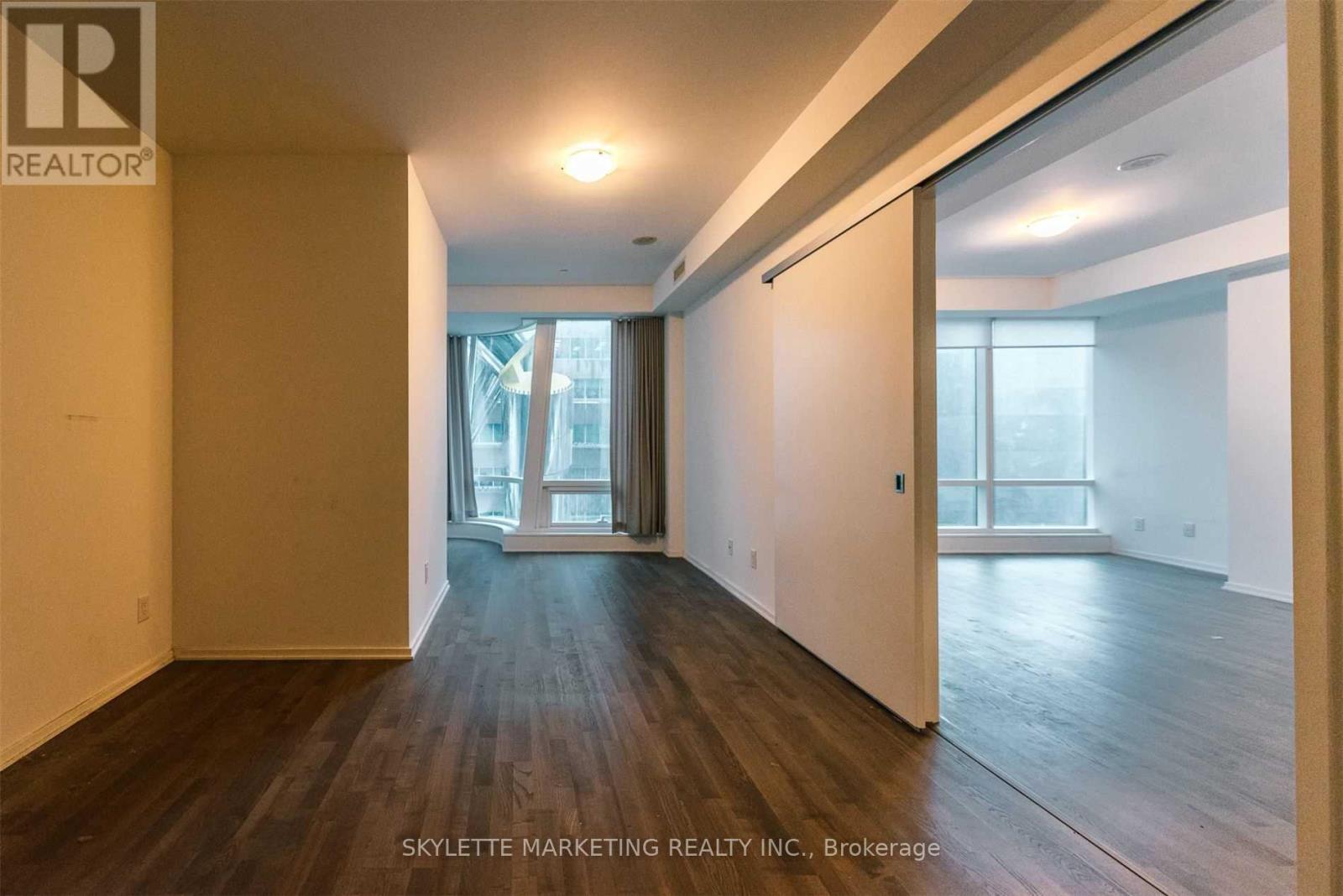 A spacious room with wooden floors and a large window.