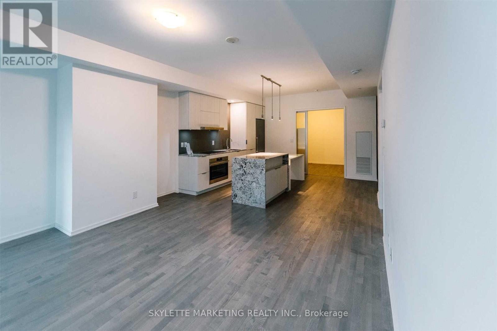 A spacious living room with a television and a kitchen area in the background.