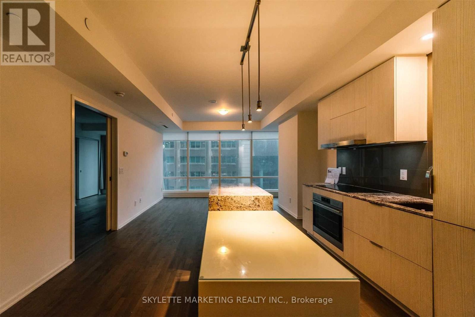 A modern kitchen with wooden cabinets and a large window.
