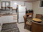 A small kitchen with a refrigerator, table and chairs.