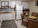 A small kitchen with a refrigerator, table and chairs.