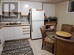 A small kitchen with a refrigerator, table and chairs.