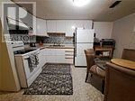 A kitchen with a white fridge and a black and white rug.