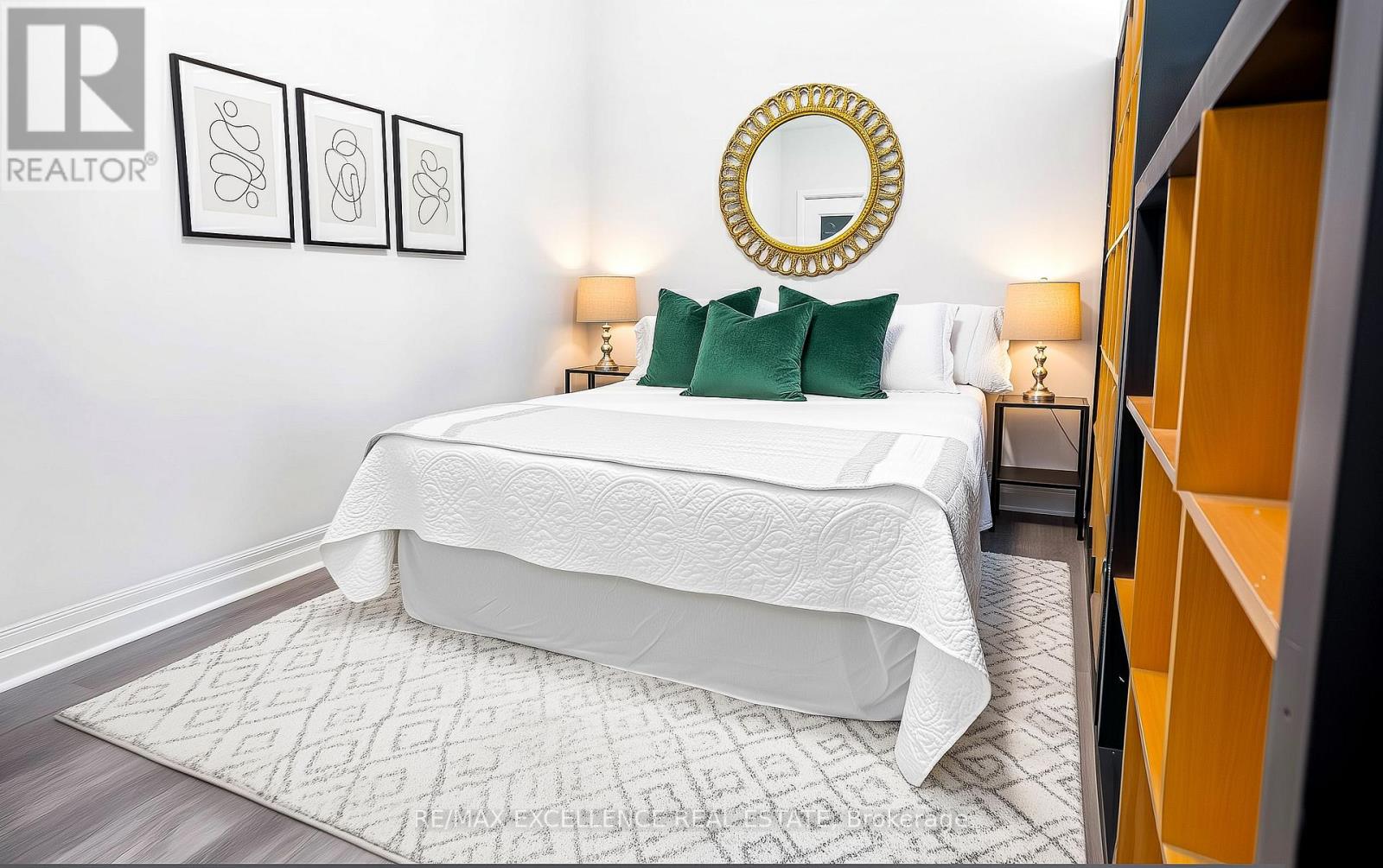 A bedroom with a white bed and a mirror above it.