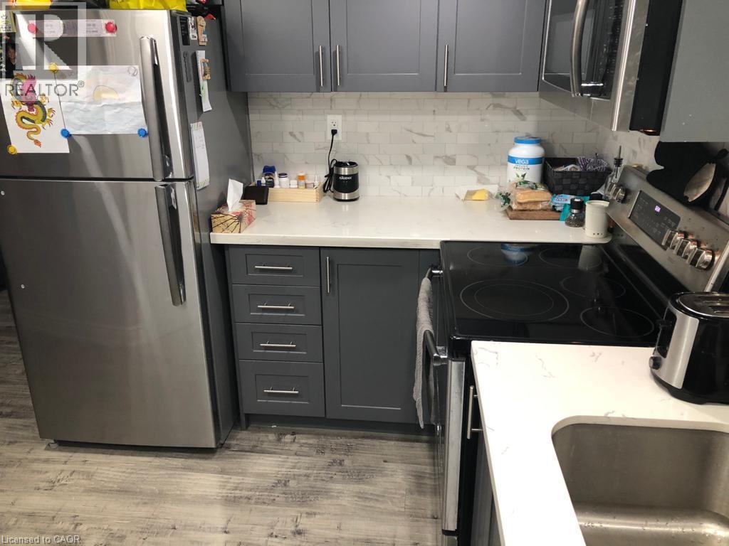 A kitchen with a refrigerator, oven, and microwave.