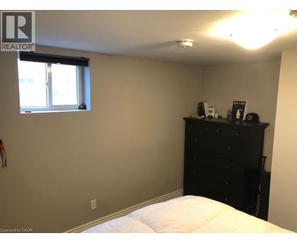 A bedroom with a bed, dresser, and window.