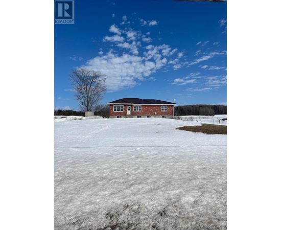 A red brick house with a white door and windows is surrounded by a snowy field.