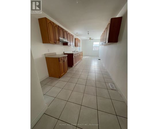 A kitchen with white tiled floors and wooden cabinets.