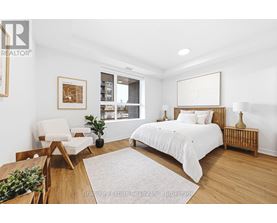 A bedroom with a bed, chair, and a potted plant.