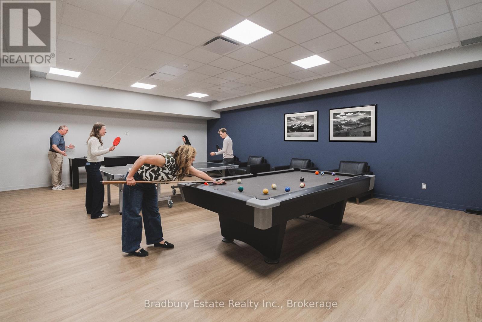A woman is playing pool in a room with a pool table and a few other people.