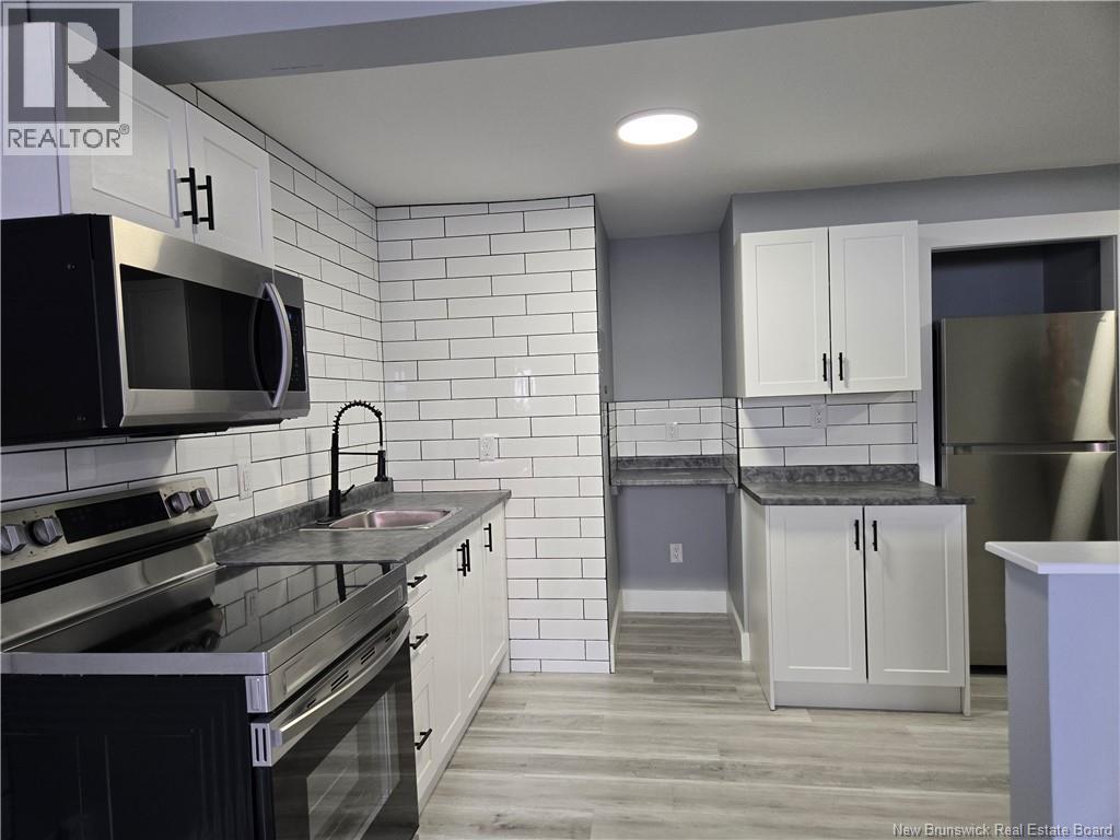 A kitchen with white cabinets and black appliances.