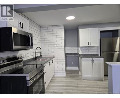A kitchen with white cabinets and black appliances.