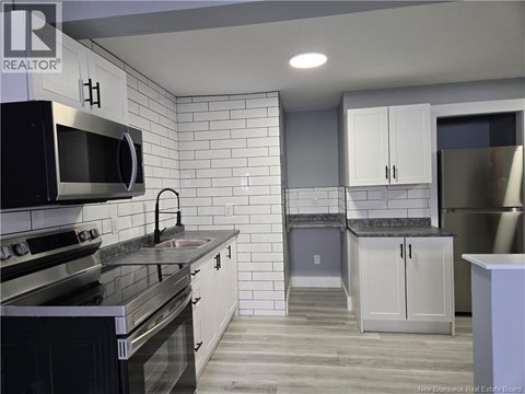A kitchen with white cabinets and black appliances.