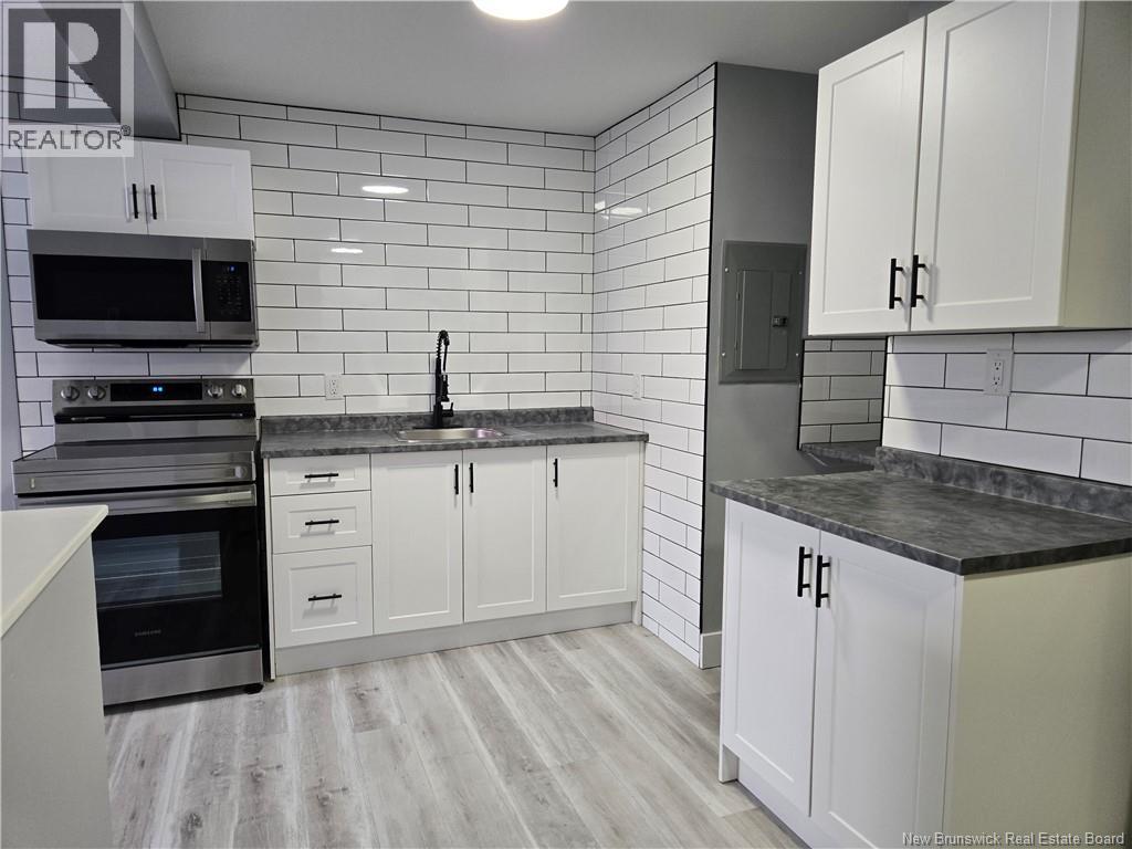 A kitchen with white cabinets and a black countertop.
