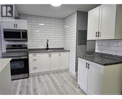 A kitchen with white cabinets and a black countertop.