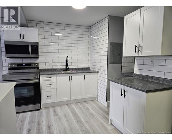 A kitchen with white cabinets and a black countertop.