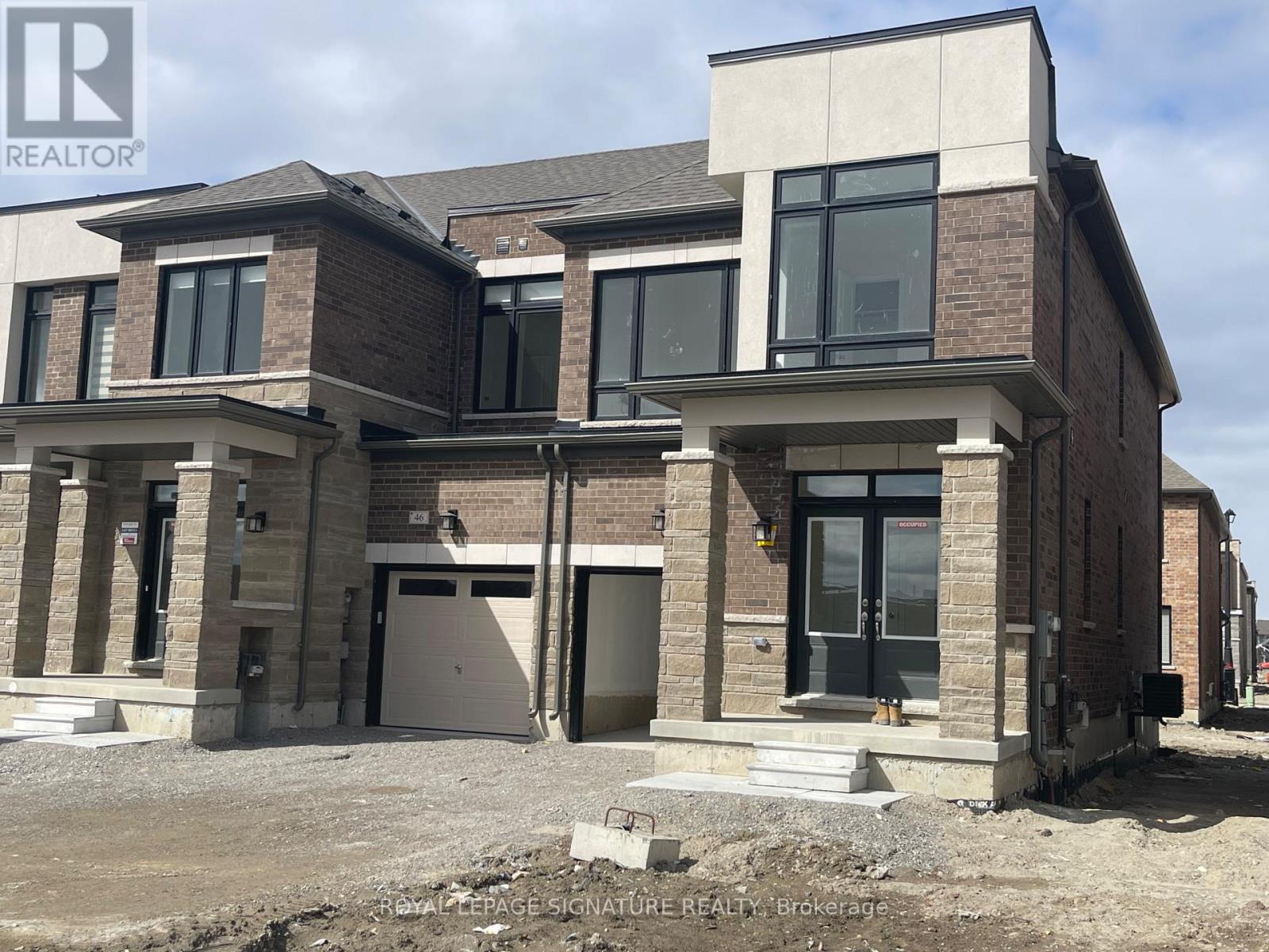 A modern house with a brick facade and large windows is under construction.
