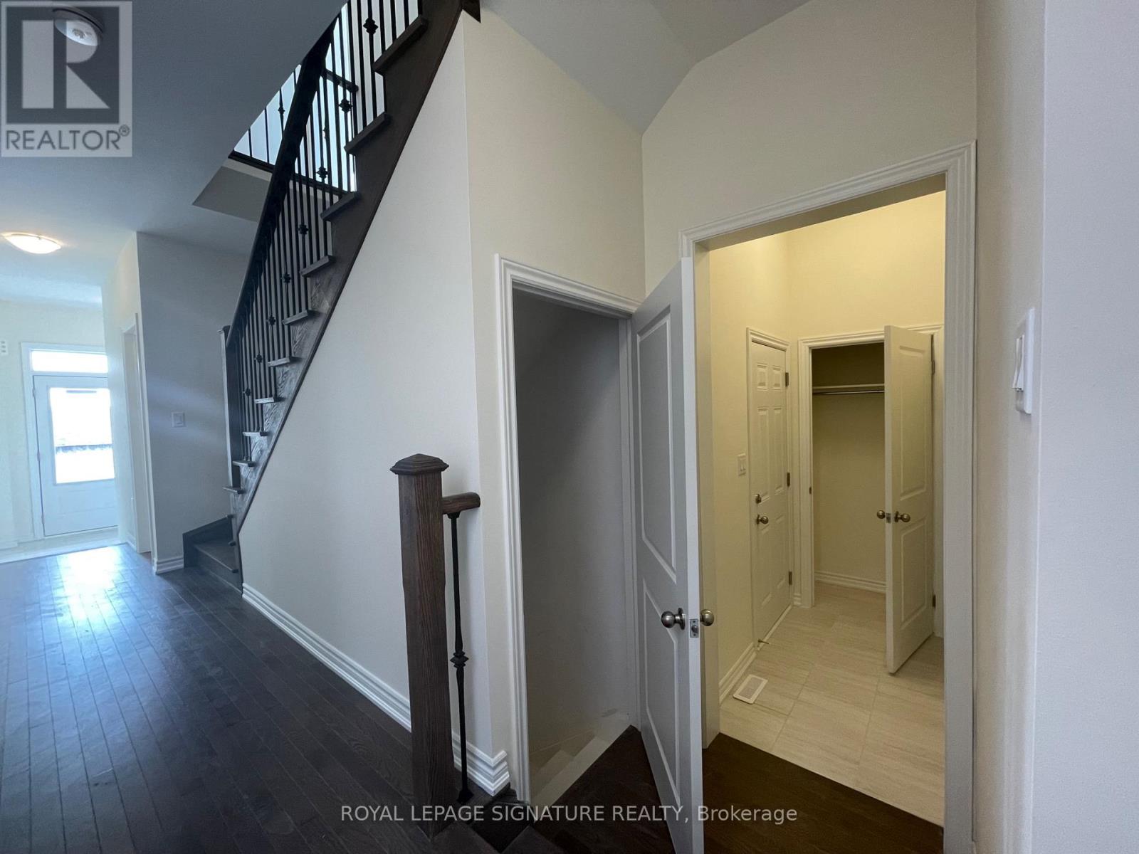 A hallway with a staircase and a doorway leading to another room.