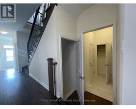 A hallway with a staircase and a doorway leading to another room.