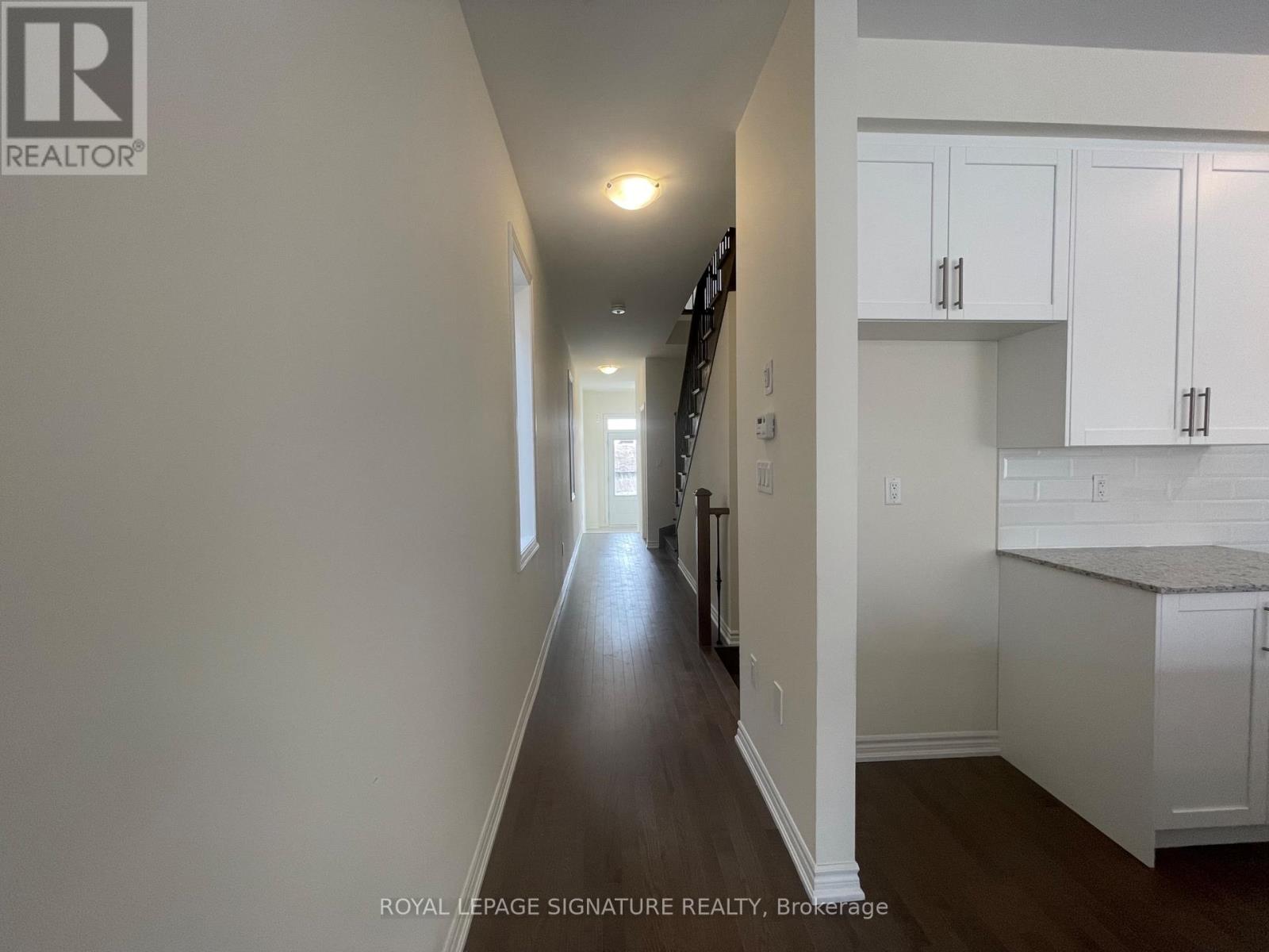 A long hallway with white walls and a wooden floor.