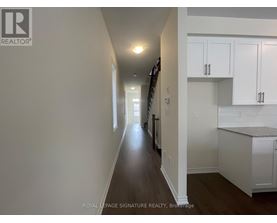 A long hallway with white walls and a wooden floor.