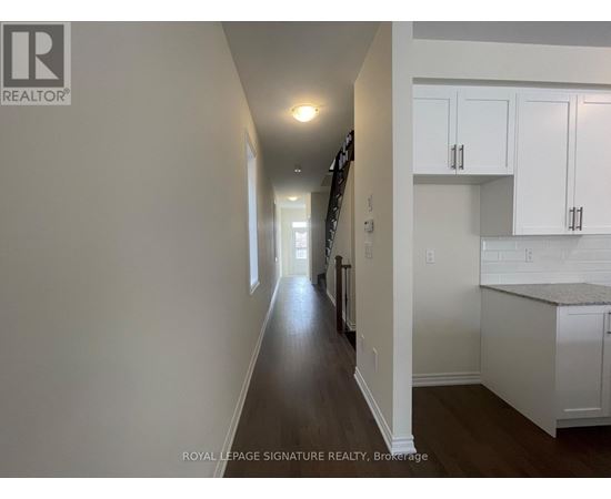 A long hallway with white walls and a wooden floor.