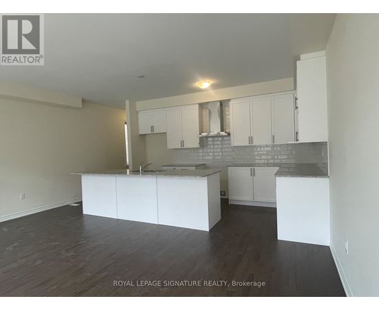 A spacious kitchen with white cabinets and a grey backsplash.