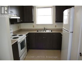 A kitchen with a stove, sink, and refrigerator.