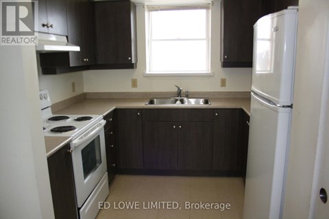 A kitchen with a stove, sink, and refrigerator.