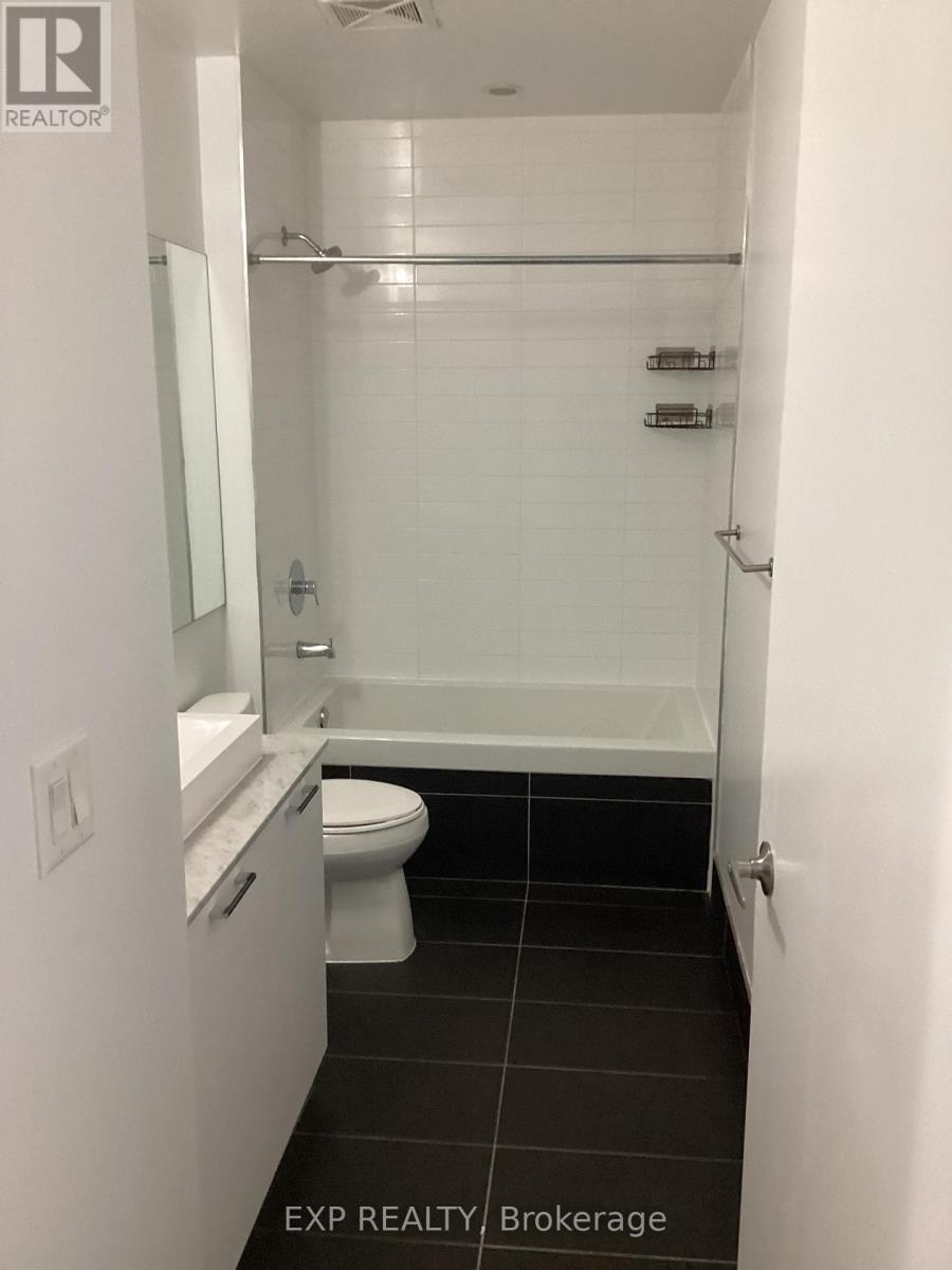 A white bathroom with a toilet, sink, and shower.