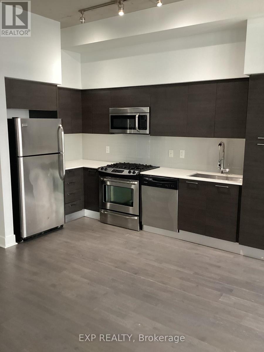 A kitchen with a refrigerator, oven, and microwave.