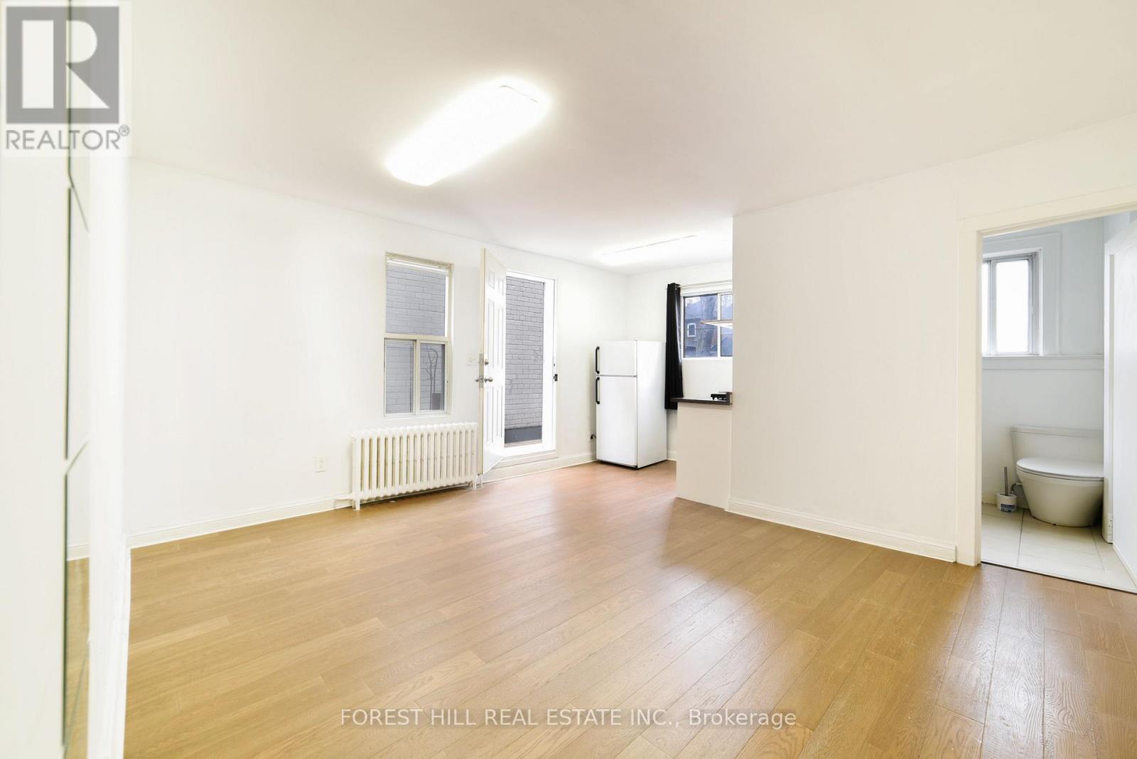 A spacious room with wooden floors and white walls.
