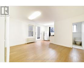A spacious room with wooden floors and white walls.