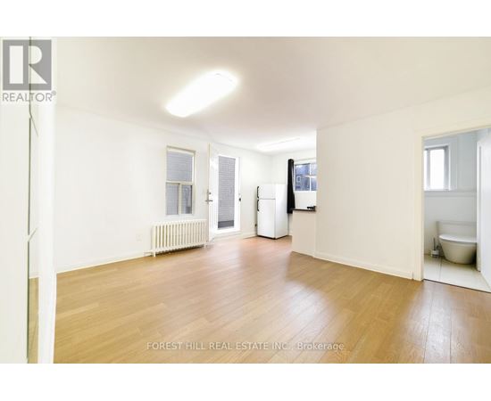 A spacious room with wooden floors and white walls.