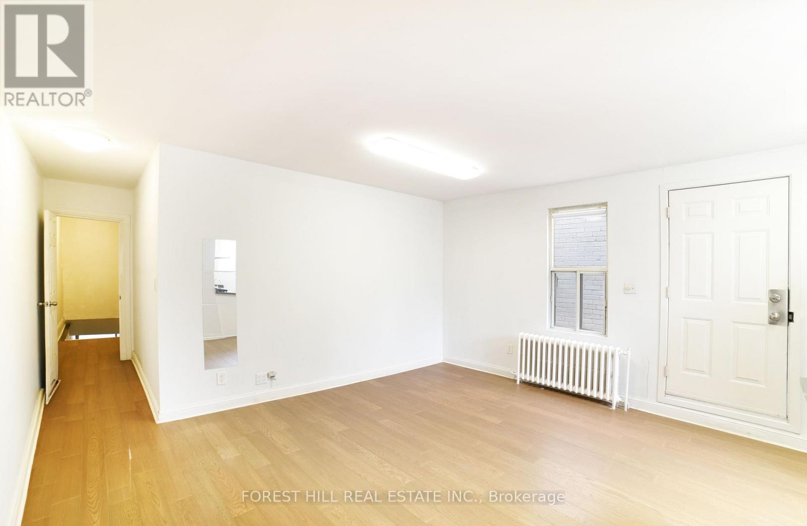 A white room with a wooden floor and a door on the right side.