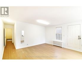 A white room with a wooden floor and a door on the right side.