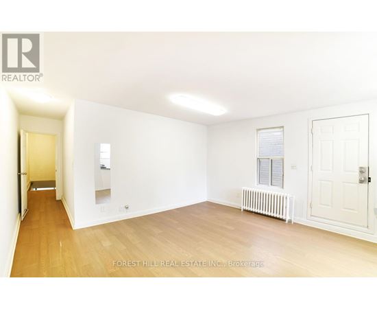 A white room with a wooden floor and a door on the right side.