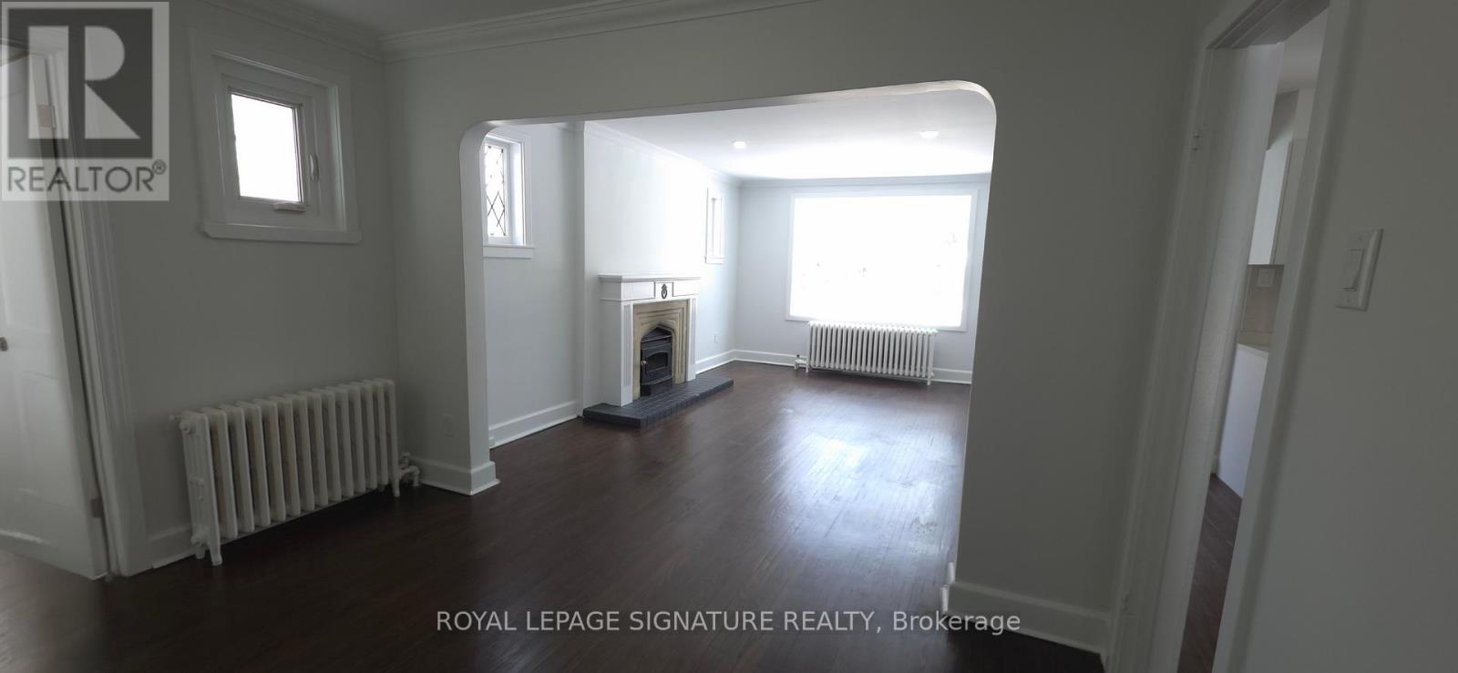 A spacious room with a fireplace and wooden floors.