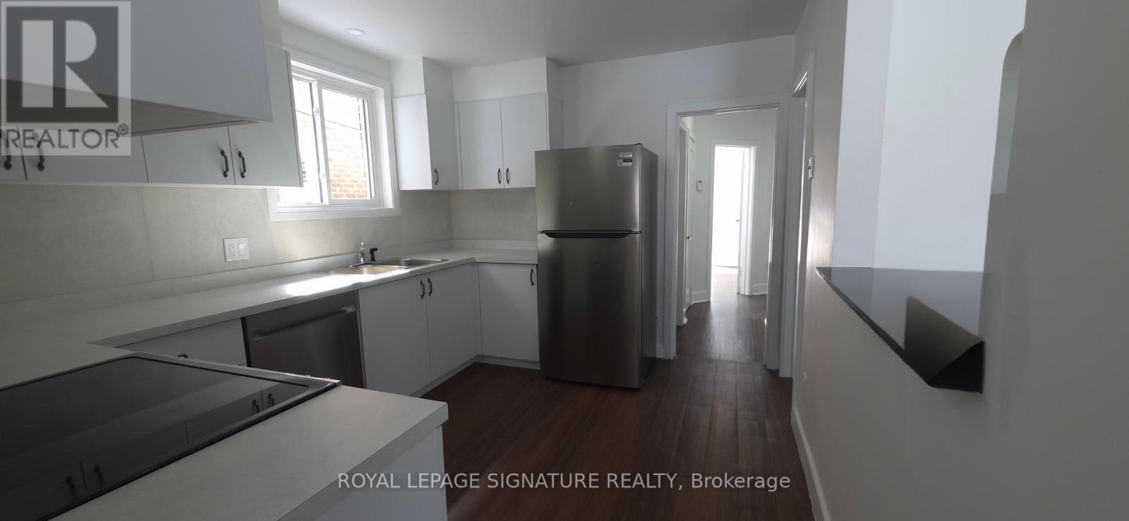 A kitchen with white cabinets and a stainless steel refrigerator.