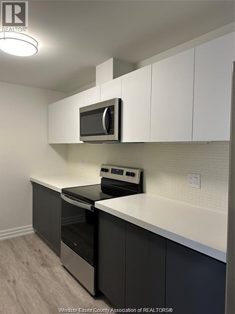 A kitchen with white cabinets and a microwave above the stove.
