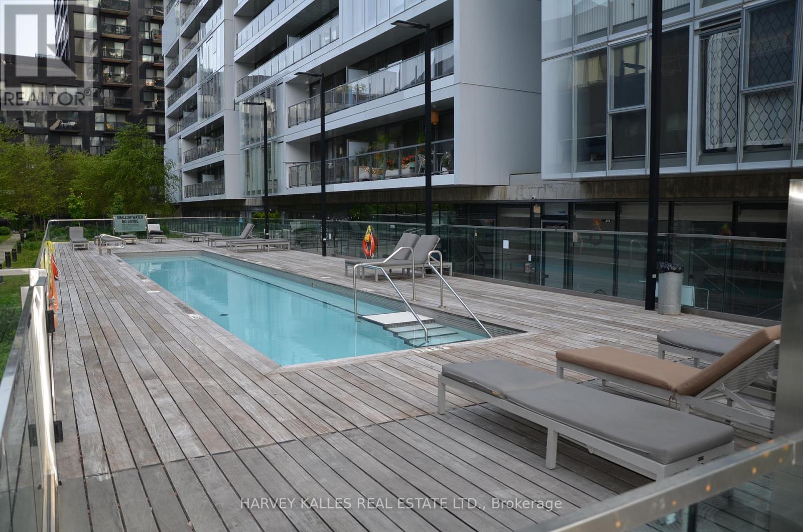A wooden deck with a pool and lounge chairs.