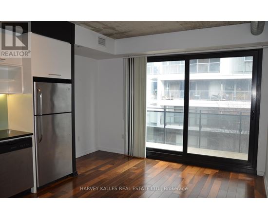 A kitchen with a stainless steel refrigerator and a sliding glass door leading to a balcony.