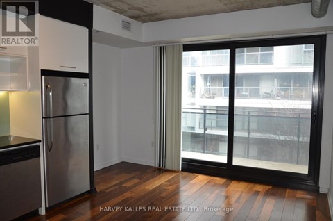 A kitchen with a stainless steel refrigerator and a sliding glass door leading to a balcony.