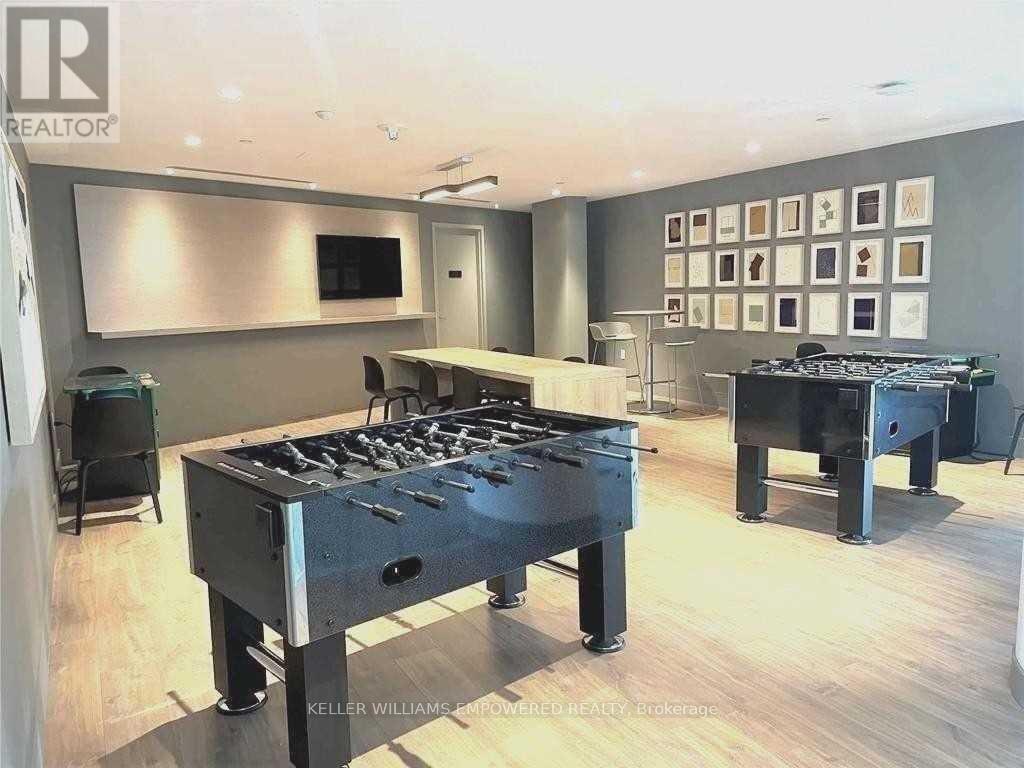 A modern living room with a foosball table and a wall of framed pictures.