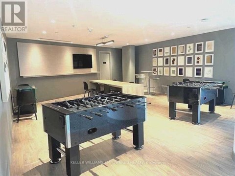 A modern living room with a foosball table and a wall of framed pictures.
